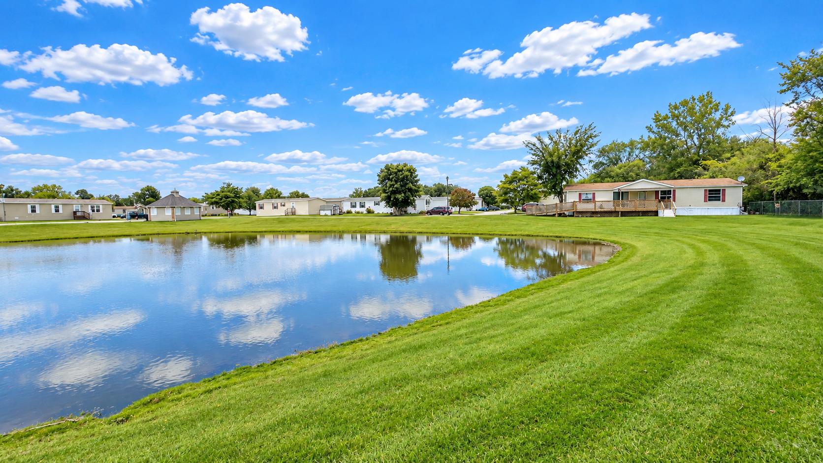 Lakeview manufactured-home community beside a pond under a blue sky